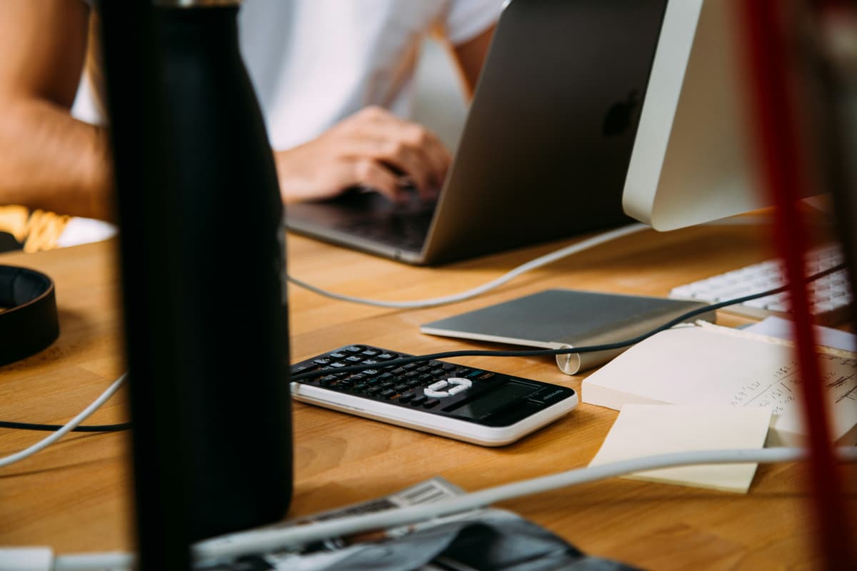 A workspace with a laptop, calculator, and notes, depicting a focused environment for accounting or financial analysis.