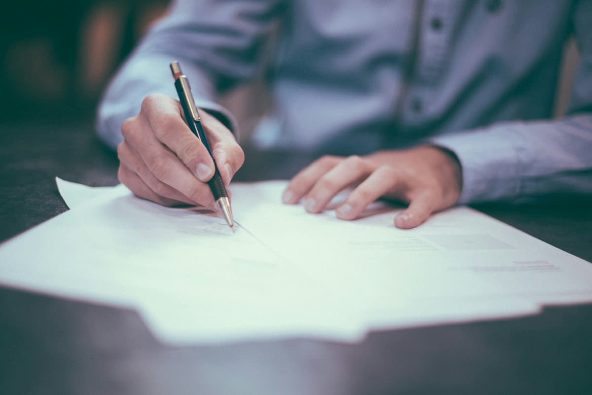 A close-up of a person writing on a document, emphasizing precision and documentation in accounting work.