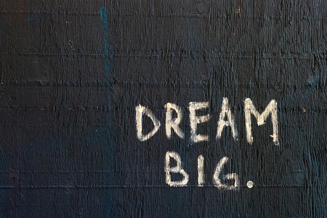 A motivational message reading 'Dream Big' written on a textured dark background, inspiring ambition and goal-setting.