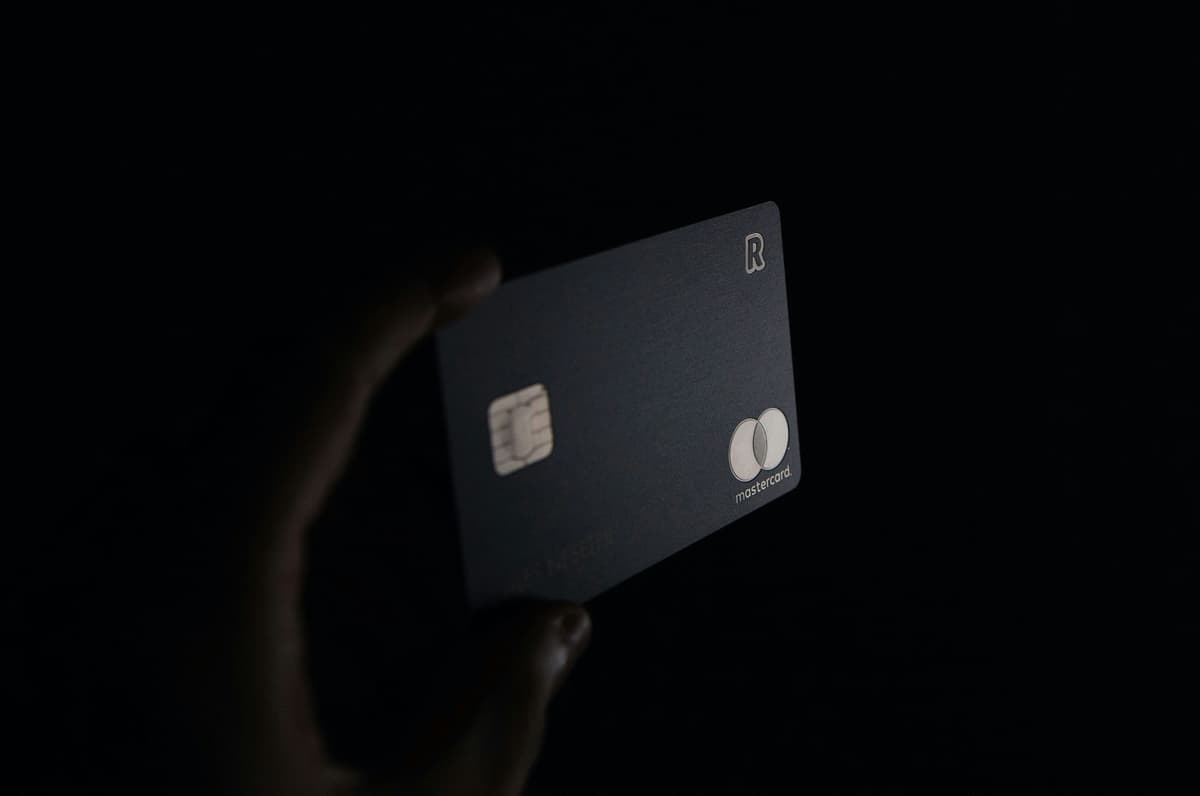 A hand holding a sleek black credit card in a dimly lit setting, symbolizing secure financial transactions and credit services.