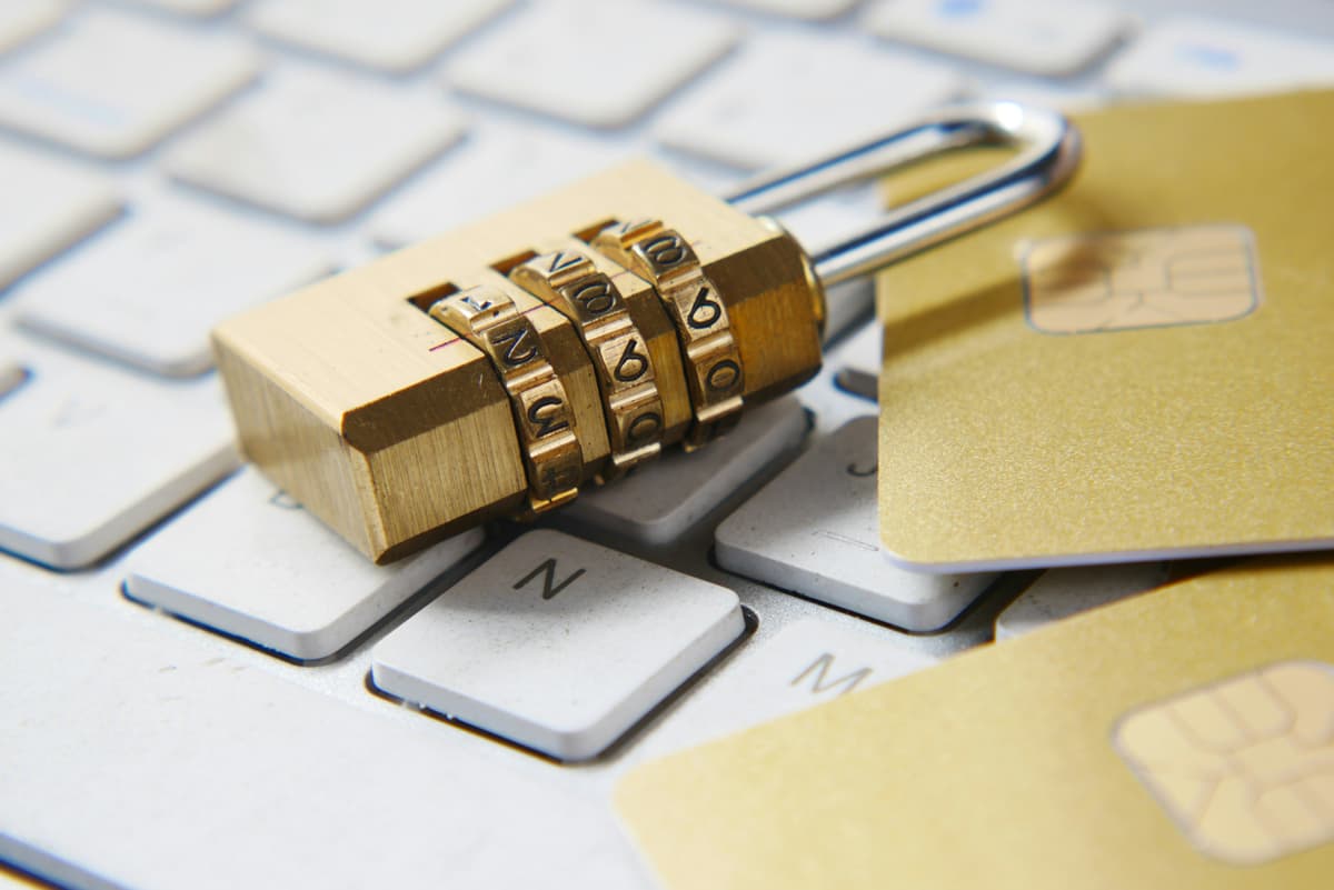 A close-up of a combination lock resting on a keyboard alongside credit cards, representing secure online payment processing.