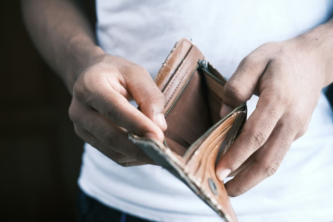 A person holding an empty wallet, signifying financial struggle or the need for budgeting.