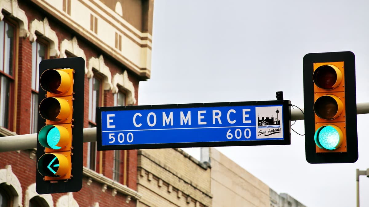 A street sign labeled 'E Commerce' with traffic lights, metaphorically representing the direction and pathways in the digital commerce industry.