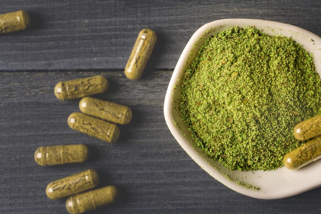 A natural presentation of kratom powder and capsules, emphasizing its organic origin with a rustic background.