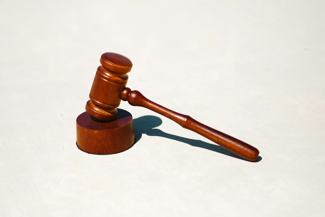 A wooden gavel placed on a matching base against a plain background, symbolizing justice and legal proceedings.