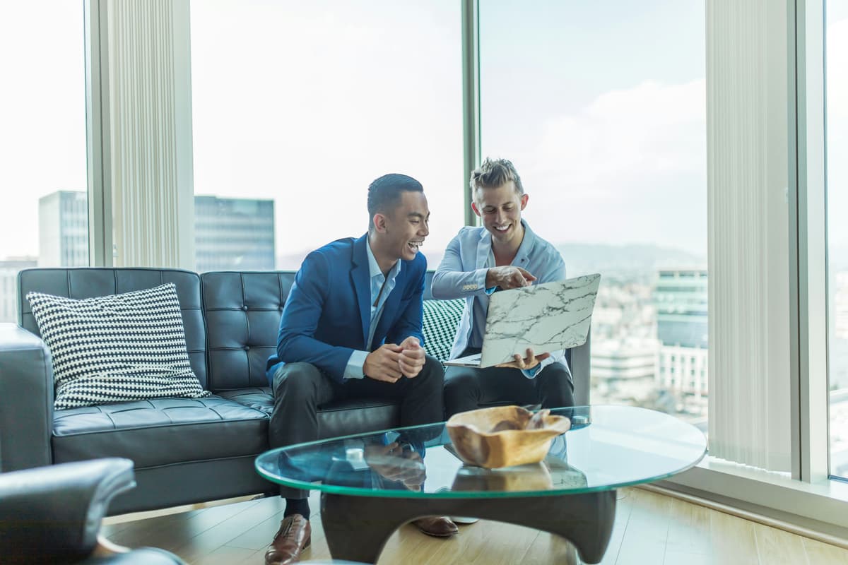 Two professionals in a bright, modern office sharing ideas on a laptop, reflecting teamwork and innovation.