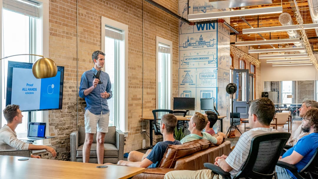 A dynamic team meeting in a creative office space with a presenter and a whiteboard, fostering collaboration and brainstorming.