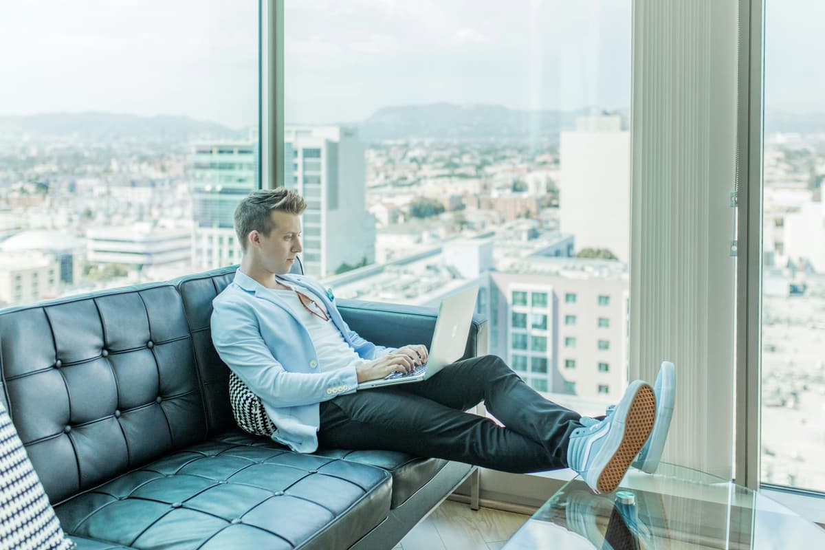 A relaxed professional working on a laptop with a panoramic view of the city, highlighting flexibility and success.