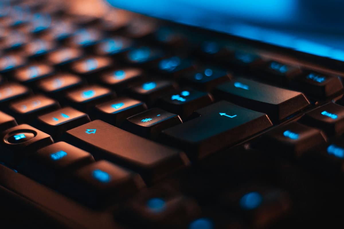 A close-up view of a backlit keyboard with illuminated keys, suggesting technology and digital infrastructure.