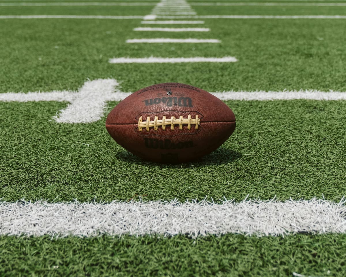 Close-up of a football on a green field with white lines, symbolizing sports and betting.