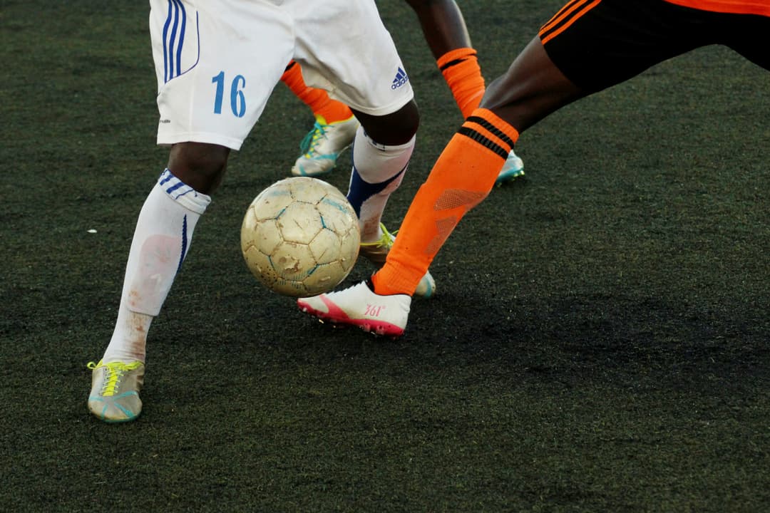 Soccer players in action, showcasing a competitive match and focus on the ball.