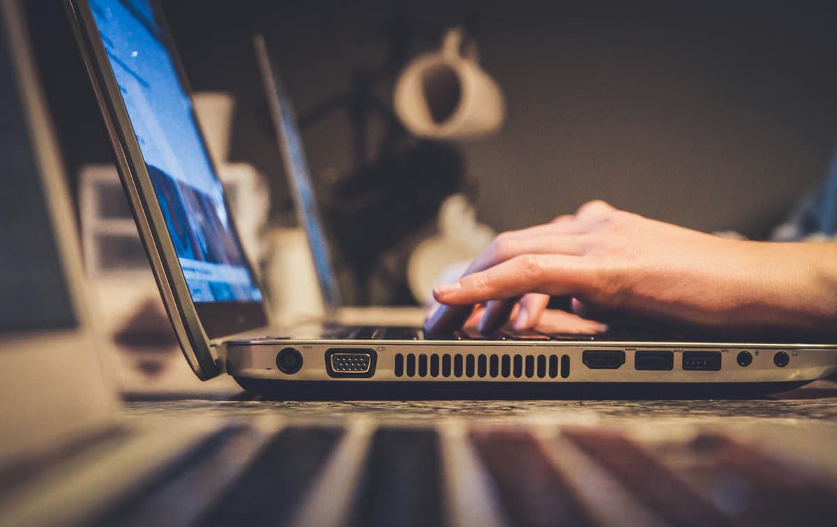 Person using a laptop to access online platforms for sports betting and game statistics.