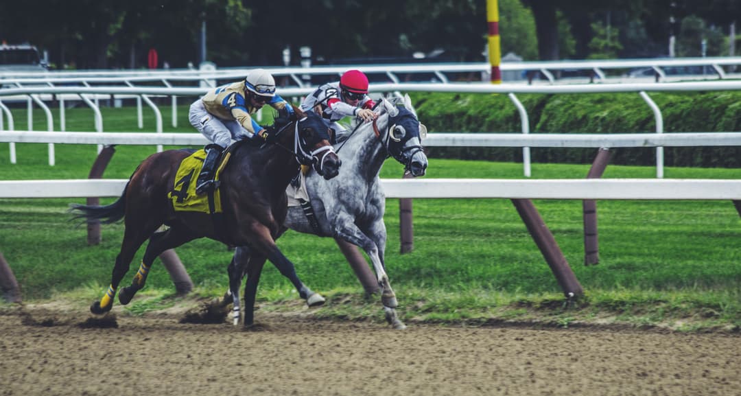 Horses racing on a dirt track with jockeys competing for the lead in a thrilling event.