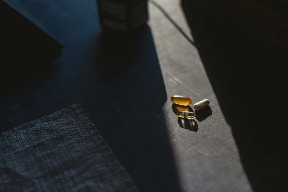 A dramatic shot of dietary supplements on a dark surface with a beam of light highlighting the capsules.