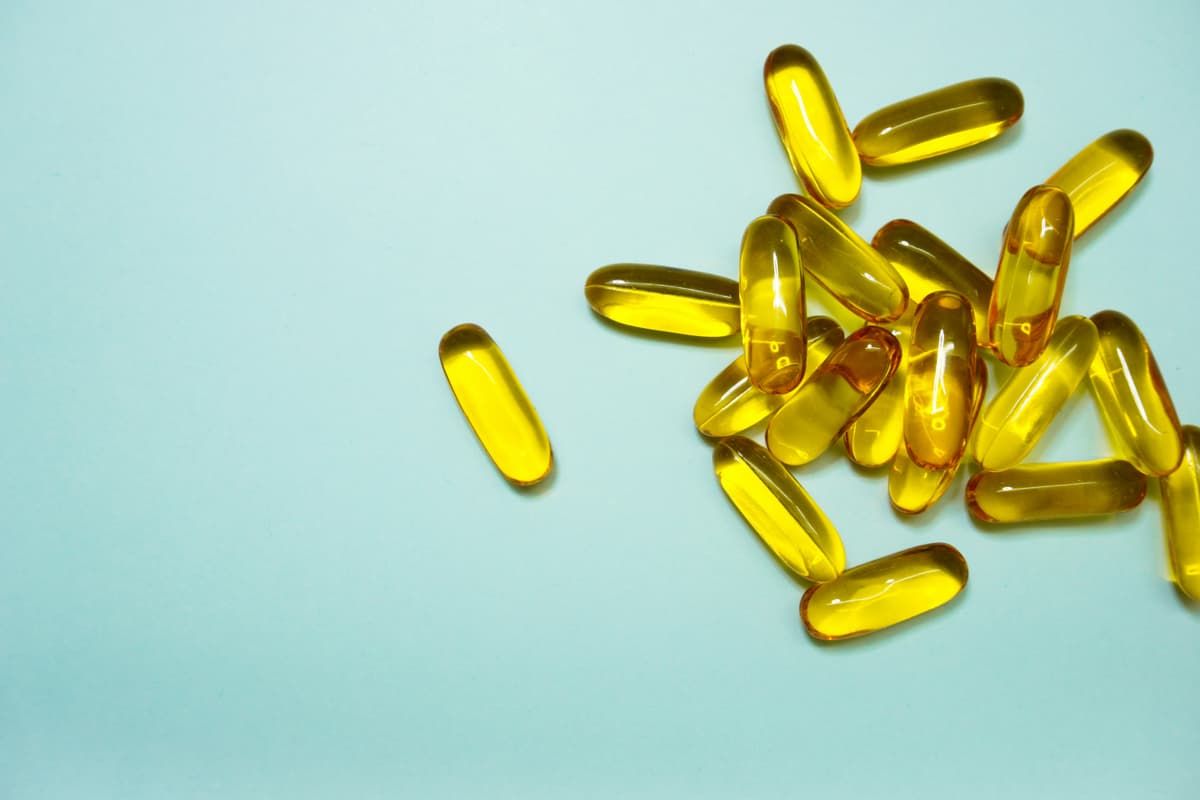 A cluster of bright yellow softgel capsules arranged on a pastel blue background.