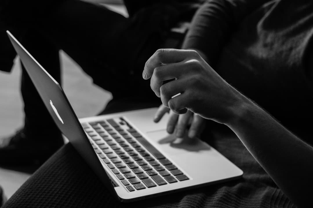 A monochrome scene of a person using a laptop, emphasizing focus and productivity.