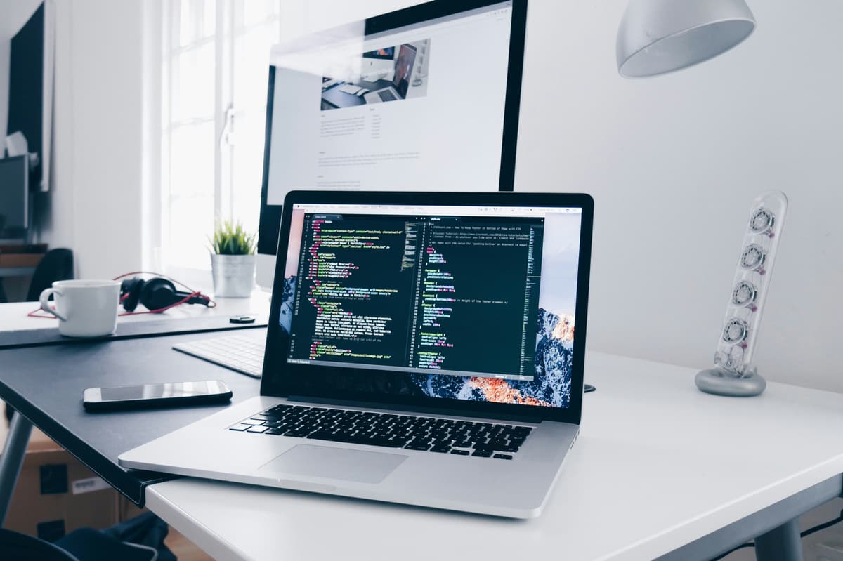 A laptop with programming code on the screen, surrounded by a modern office setup, representing software development or system integration.